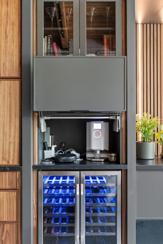 Contemporary entertainment center with gray painted cabinets and stained slatted back wall behind a large mounted tv.